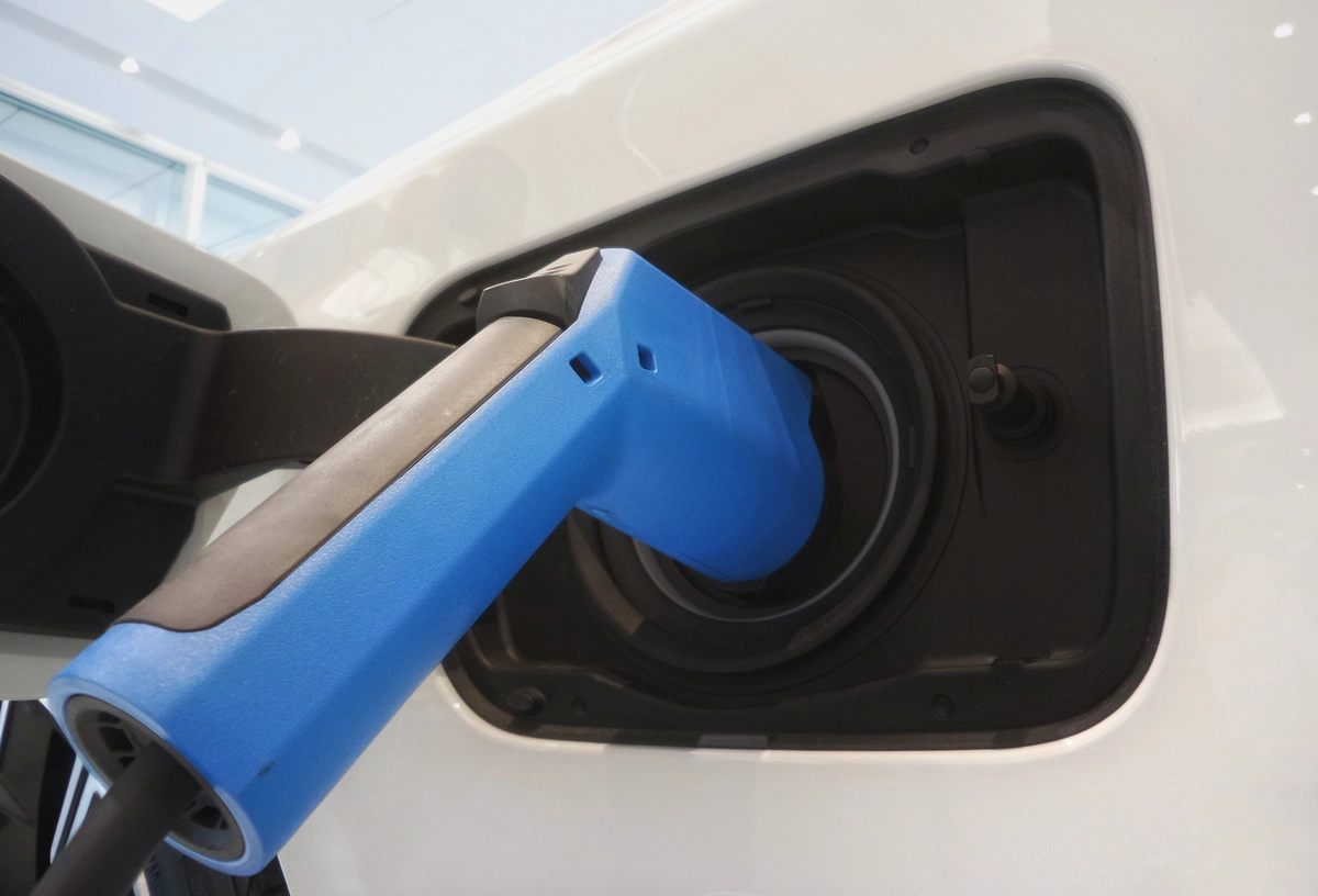 Close up of an electric vehicle's charging port plugged in to a charging station.