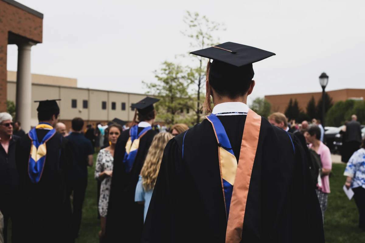 A group of recent college graduates dressed in caps and gowns, with honors regalia.